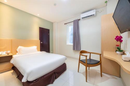 马卡萨Life Hotel Soekarno Hatta Makassar的一间卧室配有一张床、一张桌子和一把椅子