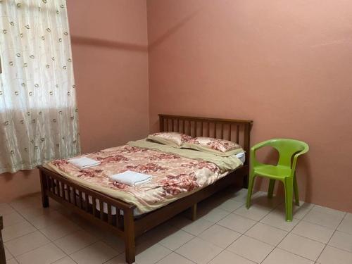 TamparuliNaVita Homestay的一间卧室配有一张床和一把绿色椅子