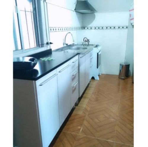 科斯塔阿苏尔Lo de Sandra的厨房配有白色橱柜和黑色台面