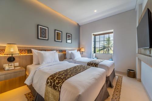 龙目岛库塔MONTANA @OCEANSIDE MANDALIKA的酒店客房设有两张床和电视。