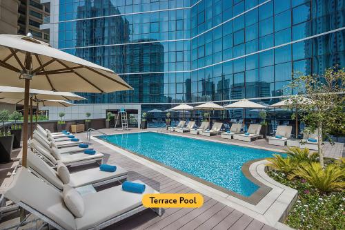 迪拜迪拜温德姆特瑞普酒店的大楼前的带椅子和遮阳伞的游泳池
