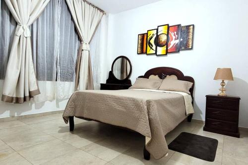 SucúaLa Perla House的一间卧室配有床、镜子和窗帘