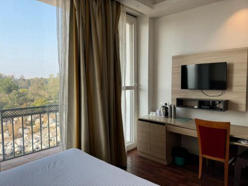 康格拉Hotel River Retreat的酒店客房设有一张书桌和一个大窗户。
