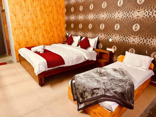 马拉里Hotel Kanchan Classic Manali的一间卧室设有两张床和一堵墙