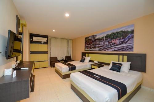 丹戎槟榔OYO 2487 Sampurna Jaya Hotel的酒店客房配有两张床和一张书桌