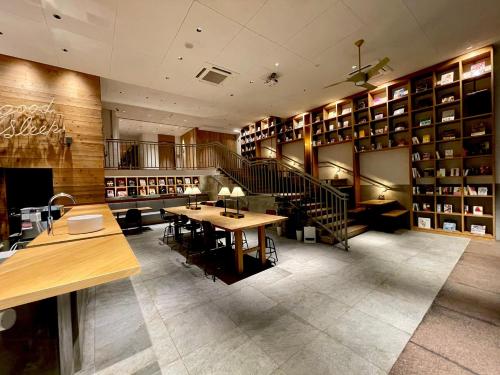 北九州Relief Kokura ANNEX Book & Stay的图书馆配有桌椅和书架