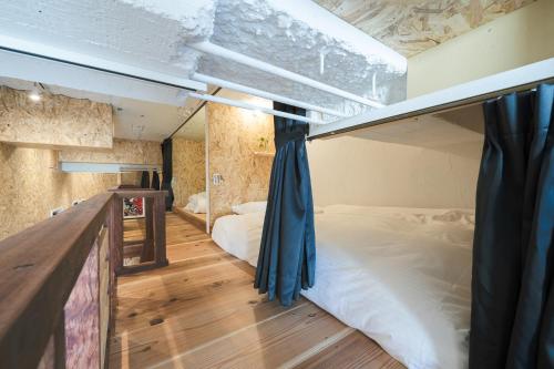 琴平町Kotori Coworking & Hostel Kotohira的一间卧室设有两张双层床,铺有木地板。
