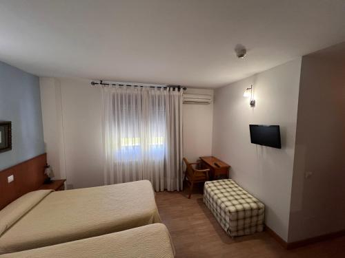 萨莫拉Hotel Puente de Piedra的酒店客房配有一张床、一把椅子和一台电视。