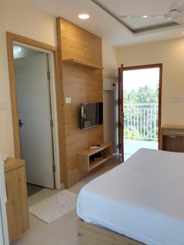 古鲁瓦尤尔Ambalath Ayesha Homes的卧室配有白色的床和电视。