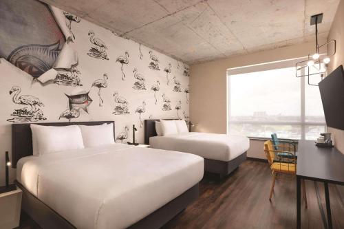 迈阿密Radisson RED Miami Airport的酒店客房设有两张床、一张书桌和一个窗户。