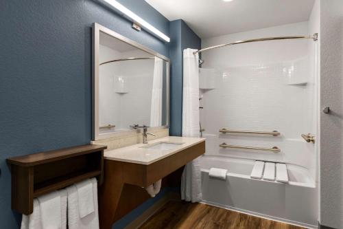 纽波特纽斯WoodSpring Suites Yorktown Newport News的一间带水槽、浴缸和镜子的浴室