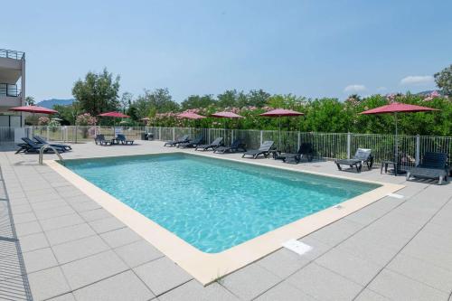 曼德琉-拉纳普勒Zenitude Hôtel-Résidences - Confort Cannes Mandelieu的一个带椅子和遮阳伞的游泳池
