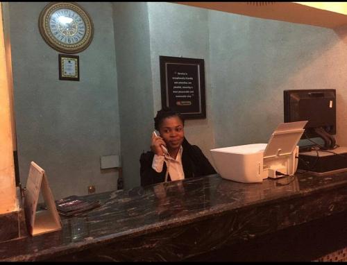 奥韦里The Resident Hotel的坐在柜台旁的一位女士在手机上讲话