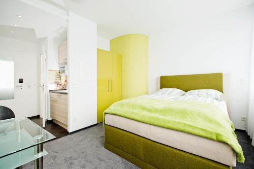 科隆设计斯利普公寓式酒店的一间卧室配有绿色的床和玻璃桌