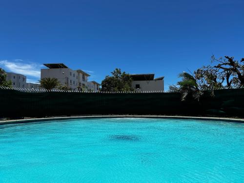 圣丹尼斯Grand Studio Le Modern Jungle - Résidence Les Jacquiers的一个大型蓝色游泳池,其建筑背景为: