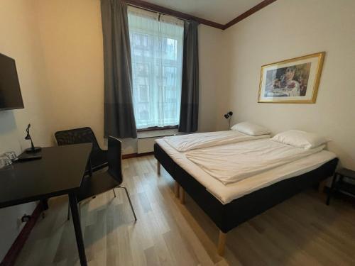 奥斯陆P酒店的一间卧室配有一张床、一张书桌和一个窗户。