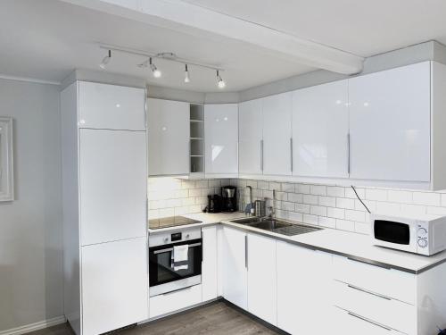 奥斯陆比斯尔特康伯尼公寓的白色的厨房配有白色橱柜和电器