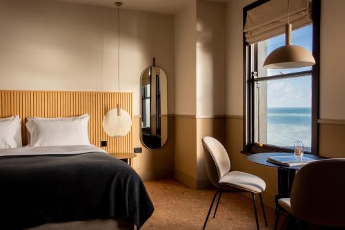伊斯特布恩Port Hotel的一间卧室配有一张床、一张桌子和一个窗户。