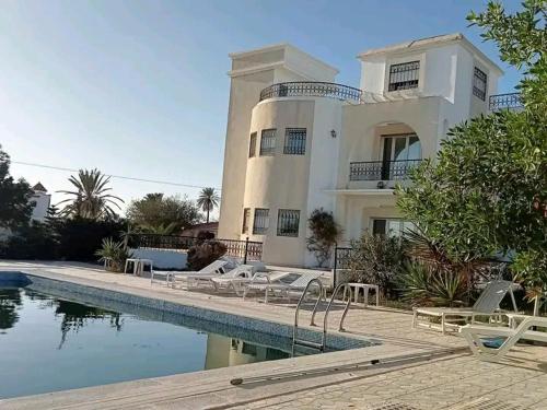 米多恩Villa Arkou Midoun的一座大型白色房子,前面设有一个游泳池