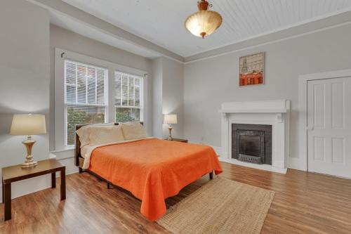 斯泰茨伯勒Historic Southern Home - close to downtown and GSU的一间卧室配有一张带橙色毯子和壁炉的床