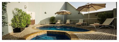 阿布扎比Executive Suites Abu Dhabi的庭院内带遮阳伞的游泳池