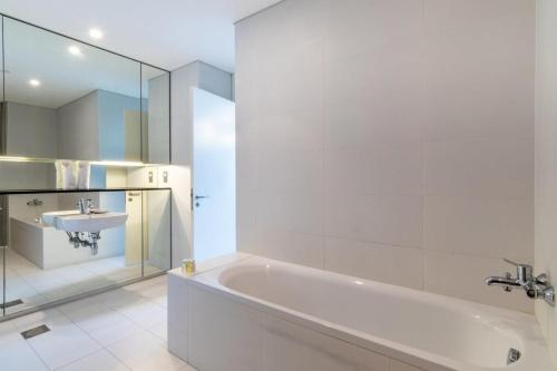 迪拜Silkhaus contemporary 1BDR with Downtown view in DIFC的白色的浴室设有浴缸和水槽。