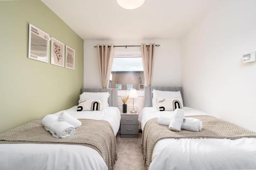 曼彻斯特6 Guests - 3 Bedrooms - Free WI-FI - Manchester的一间卧室设有两张带白色床单的床和窗户。