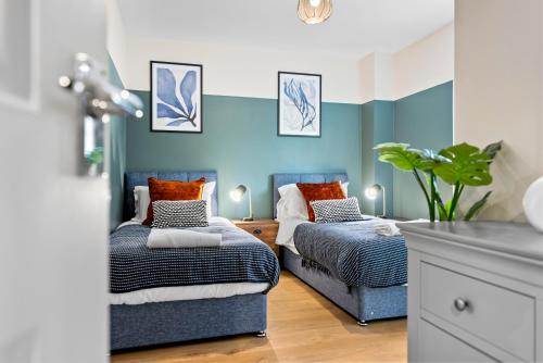 赛伦塞斯特2 bedroom apartment in the Town centre with free private parking的蓝色墙壁客房的两张床