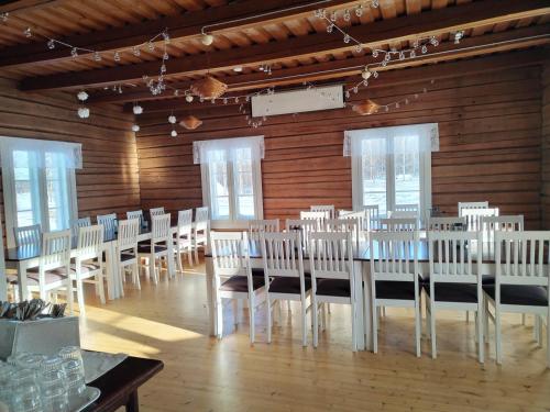 RistijärviRistijärven Pirtti Cottage Village的一间设有一排桌子和白色椅子的房间