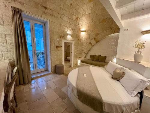 莫诺波利Vittorio Emanuele Charming Suites的卧室配有一张石墙内的大床
