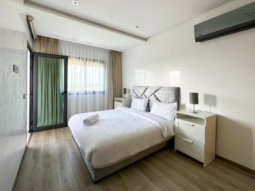 穆罕默迪耶luxe appartement met zeezicht en zwembad Mohammedia Parc的卧室设有一张白色大床和一扇窗户。