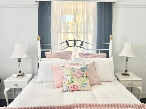 蒂默特1880 Cottage的一间卧室配有带粉色和白色枕头的床