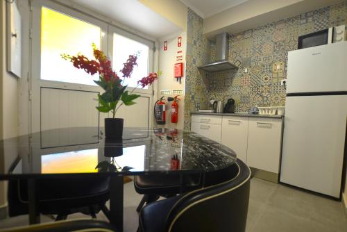 塞图巴尔Rooms DP Setúbal的厨房配有一张桌子,上面放着花瓶