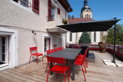 安锡OURAL Annecy Rent Lodge的一张黑色桌子、红色椅子和甲板上的遮阳伞