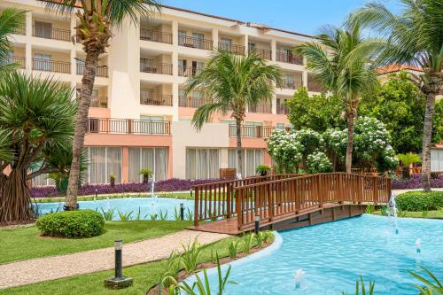 阿奎拉兹Beach Park Resort - Wellness的一座带游泳池、棕榈树和大楼的度假村