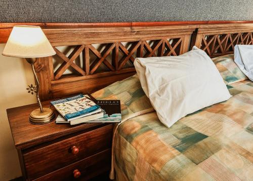 埃尔卡拉法特Lupama的一间卧室配有一张带灯具和书籍的床