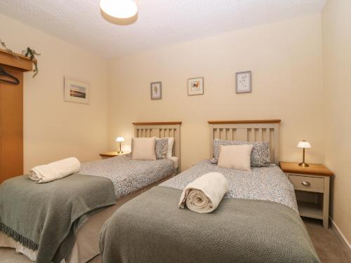 基里缪尔Steading Cottage的一间卧室配有两张带毯子和枕头的床
