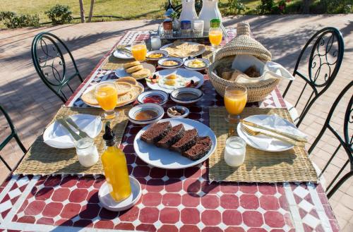 马拉喀什Ferme D'hôte Zomorroda的餐桌,带食物和橙汁盘