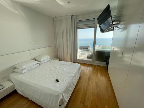 内坦亚Netanya Dream Luxury Apartment MIGDAL DAVID的一间卧室设有一张床、一台电视和一个窗口。