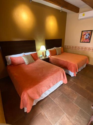 阿拉莫斯Hotel Casa María Félix的一间卧室配有两张带橙色床单的床