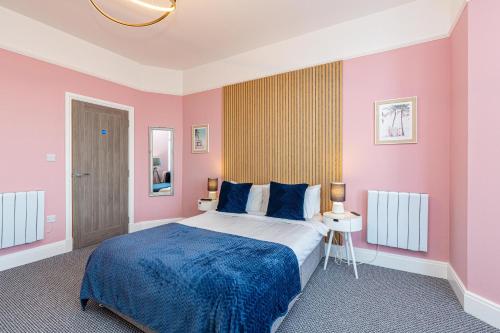 莫克姆Beachfront Apartment 3 Bedrooms Sleeps 7 - Newly Refurbished的卧室配有一张带粉红色墙壁的大床