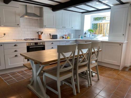 霍姆弗斯Holmfirth Hideout的厨房配有白色橱柜和木桌及椅子