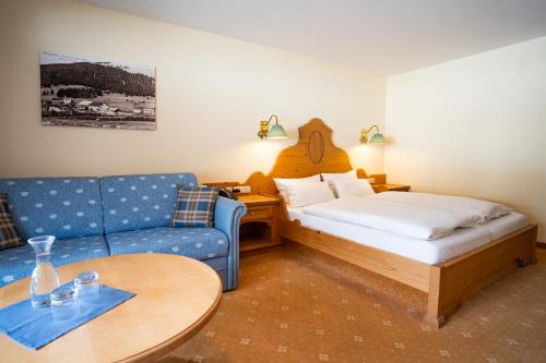 巴特欣德朗Hotel Alpengasthof Löwen的客房设有床、沙发和桌子。