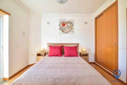阿尔布费拉Vila Alfarrobeira的卧室配有一张带粉红色枕头的大床