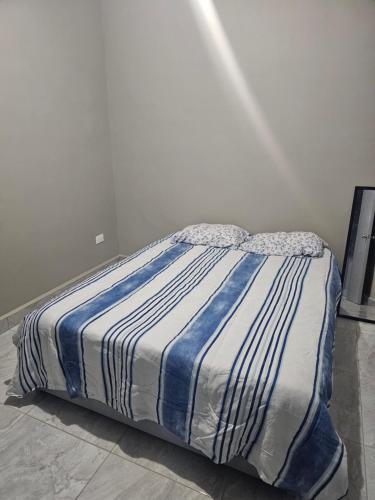马塔莫罗斯Departamento madroño的一张带蓝色和白色条纹棉被的床