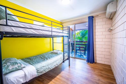埃尔利海滩The Hostel, Airlie Beach的一间卧室设有双层床和黄色的墙壁