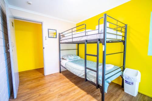 埃尔利海滩The Hostel, Airlie Beach的卧室设有两张双层床,位于黄色的墙壁上
