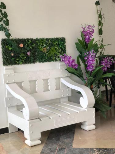 CuevasGarden Hotel的紫色花卉花园前的白色长凳
