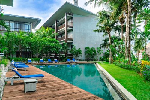克拉玛斯巴厘岛温德姆塔曼萨里吉瓦度假村的一座带躺椅的度假游泳池和一座建筑