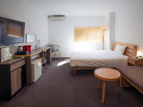 鹿儿岛You Style Hotel MARINE的酒店客房配有一张床、一张书桌和一台电视。